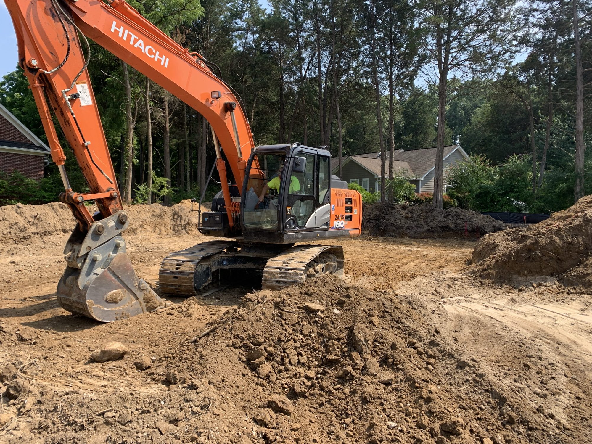 Excavator moving soil across a cleared construction site