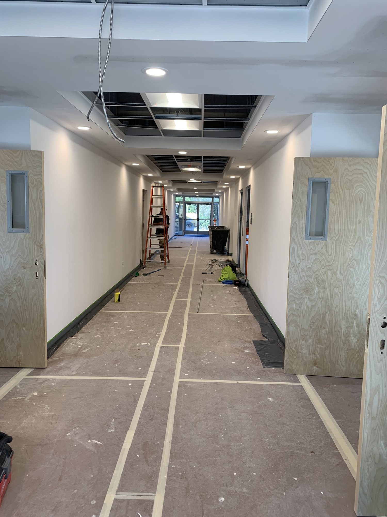 Long corridor under renovation with protected flooring and unfinished walls