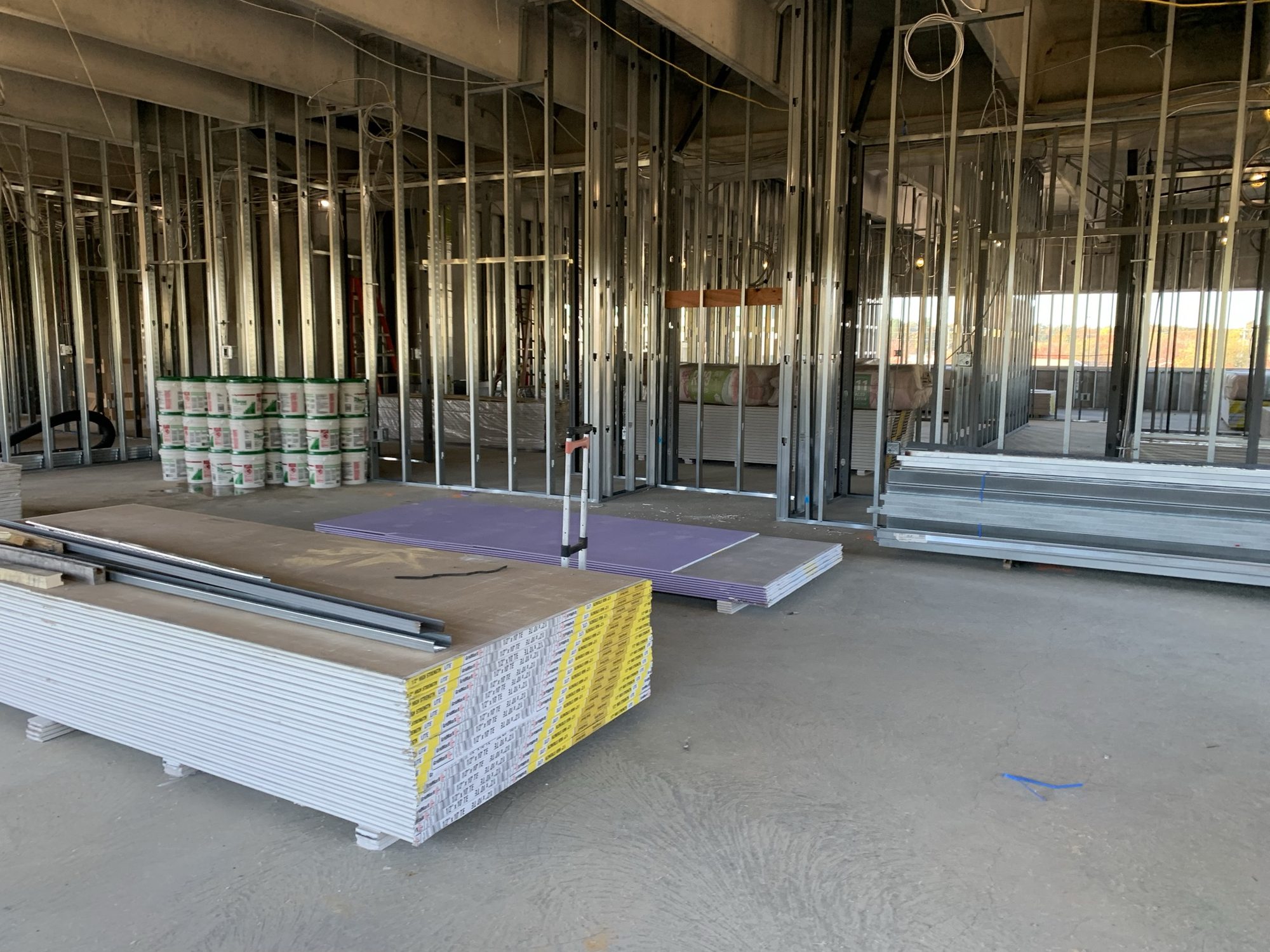 Stacks of wallboard beside newly framed metal-stud interior partitions