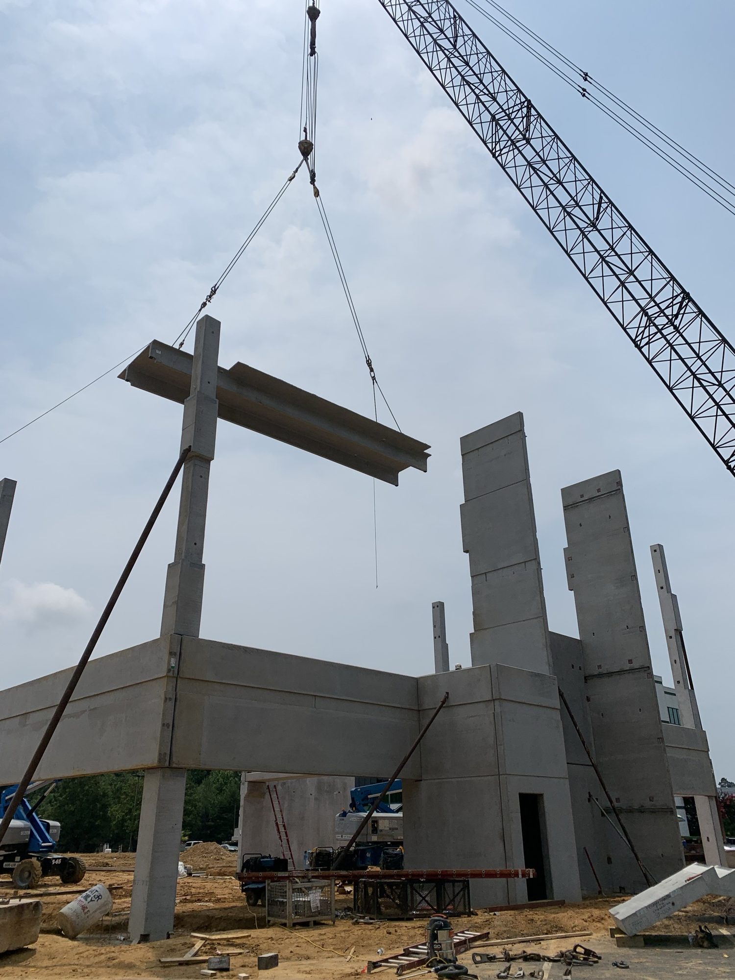 Crane lifting a concrete structural member between precast columns