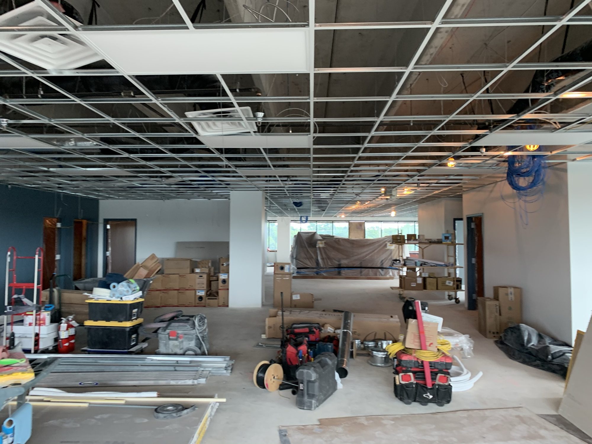 Active interior renovation with open ceiling, equipment, and materials staged across the floor
