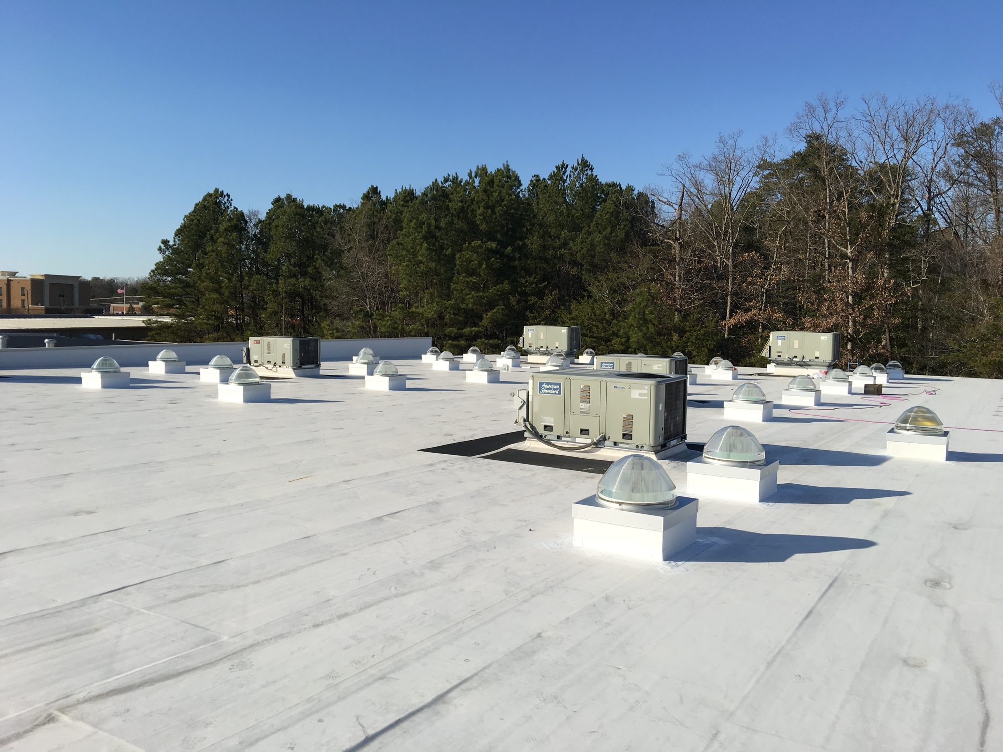 White commercial roof with mechanical equipment and new roof penetrations