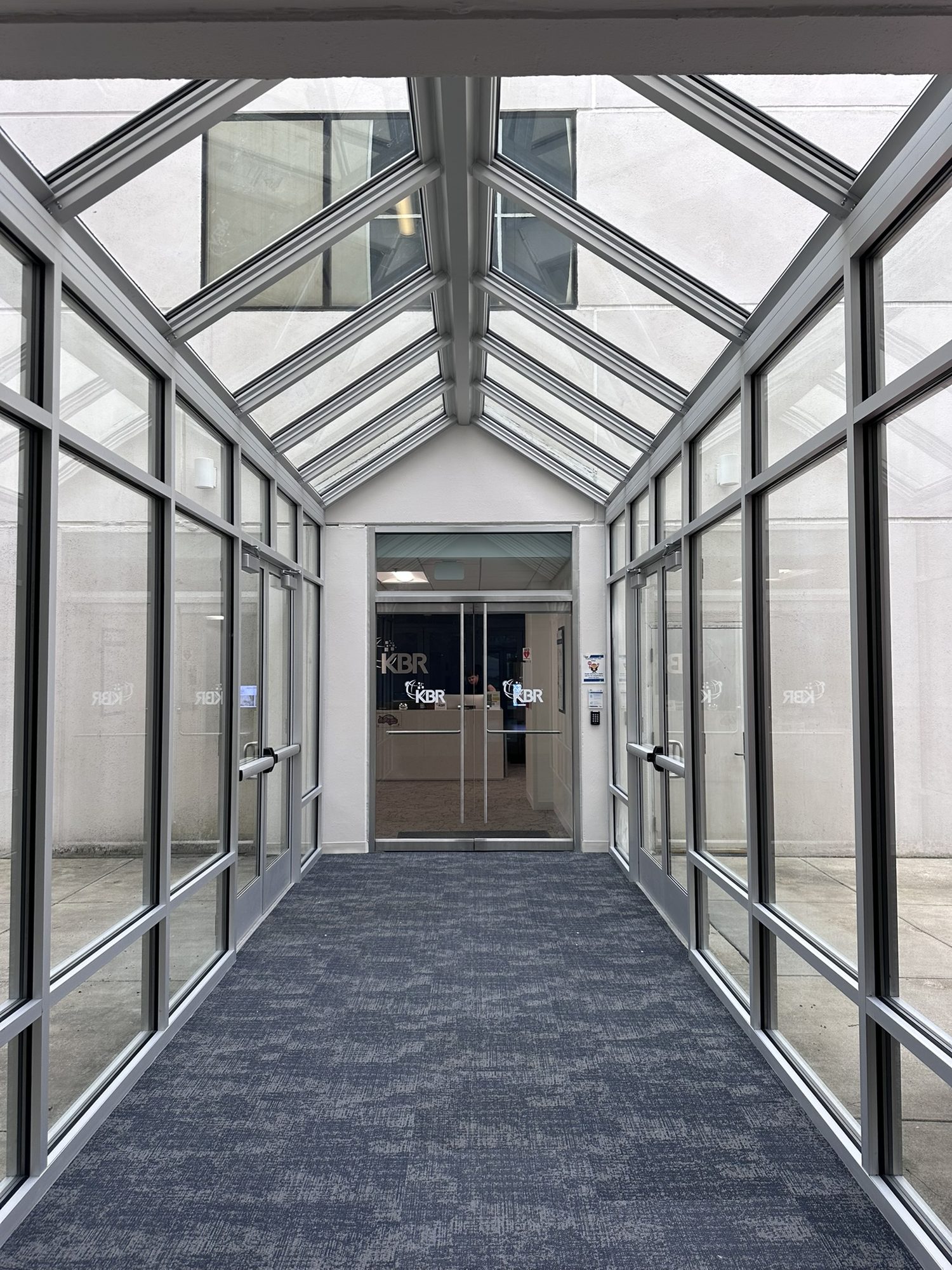 Finished glazed passage with sloped window framing and patterned carpet