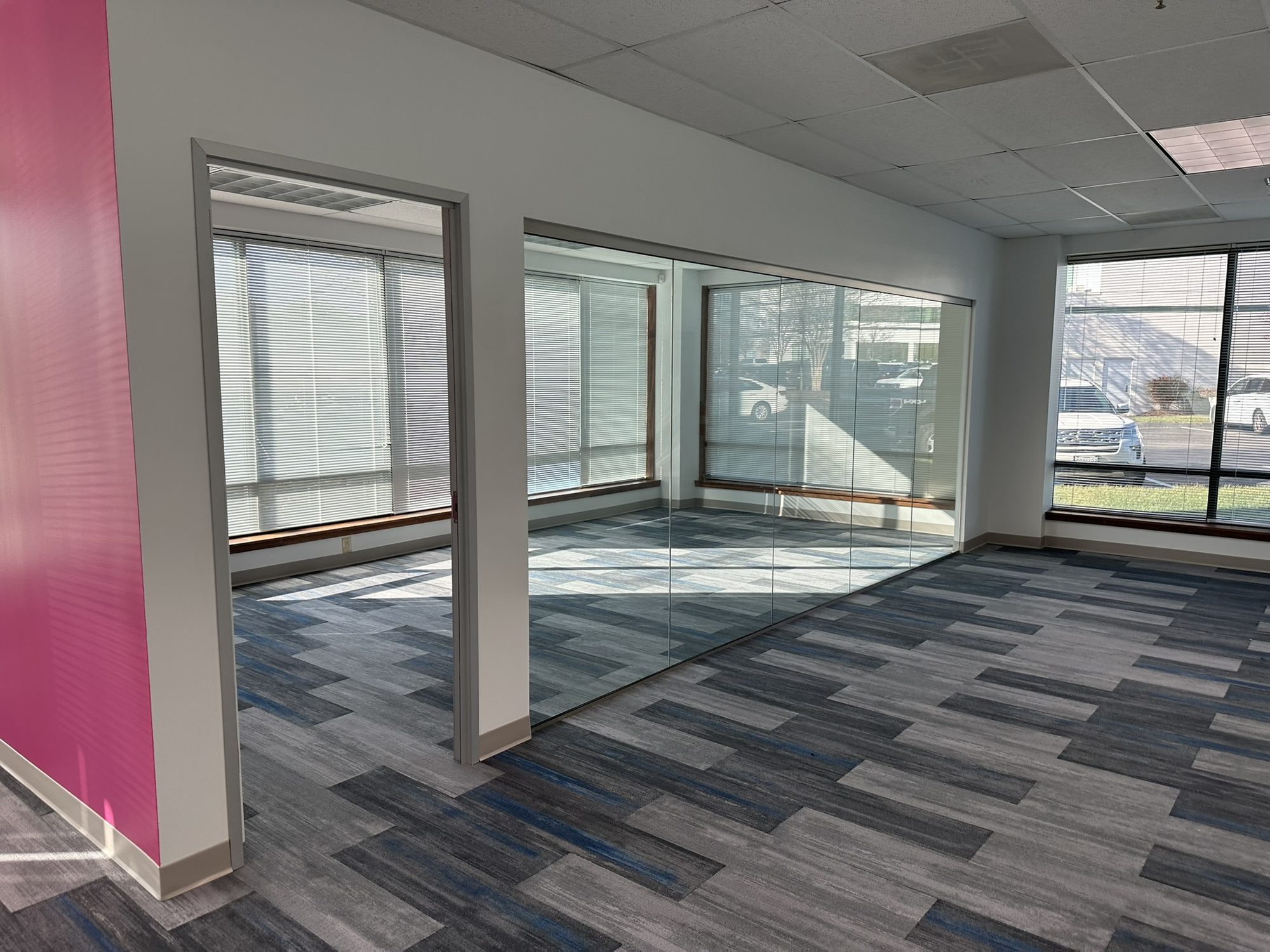 Completed offices with glass partitions, patterned carpet, and natural light