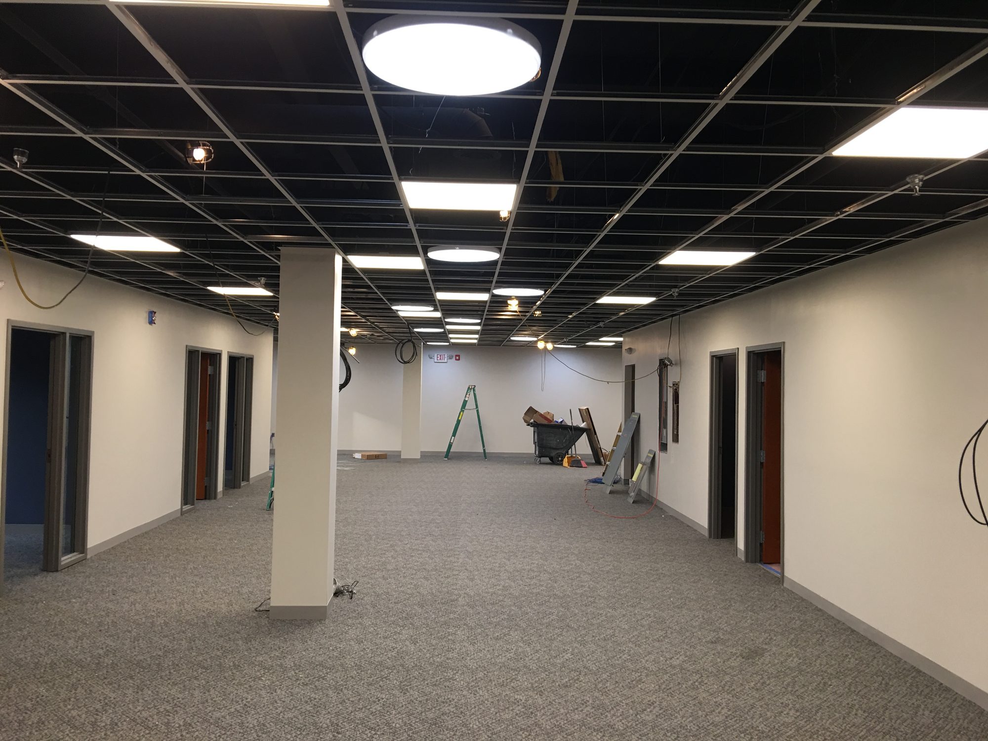 Completed office corridor with dark ceiling grid and circular light fixtures