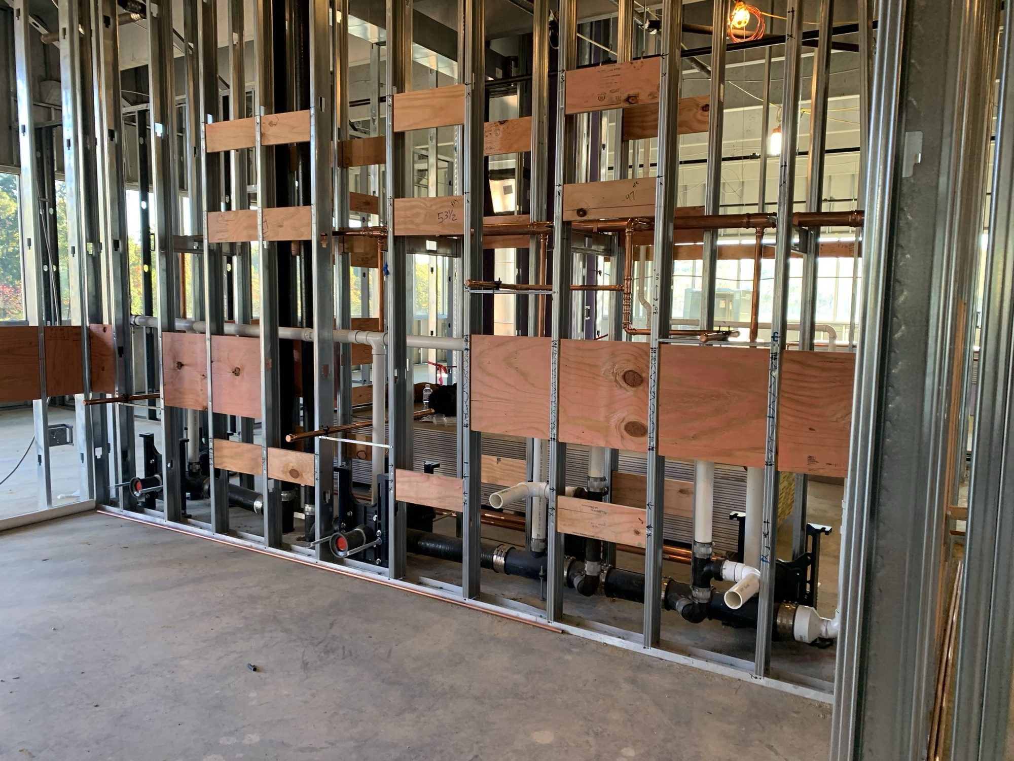 Exposed plumbing and services installed within metal-stud walls