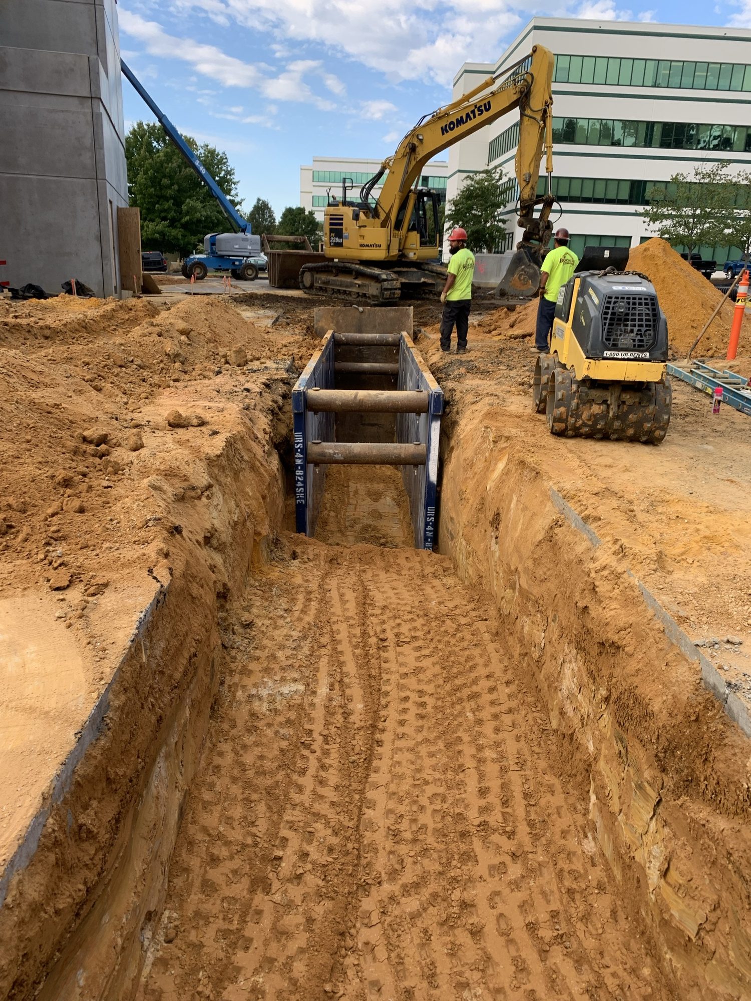 Excavator beside utility pipes laid in a deep site trench