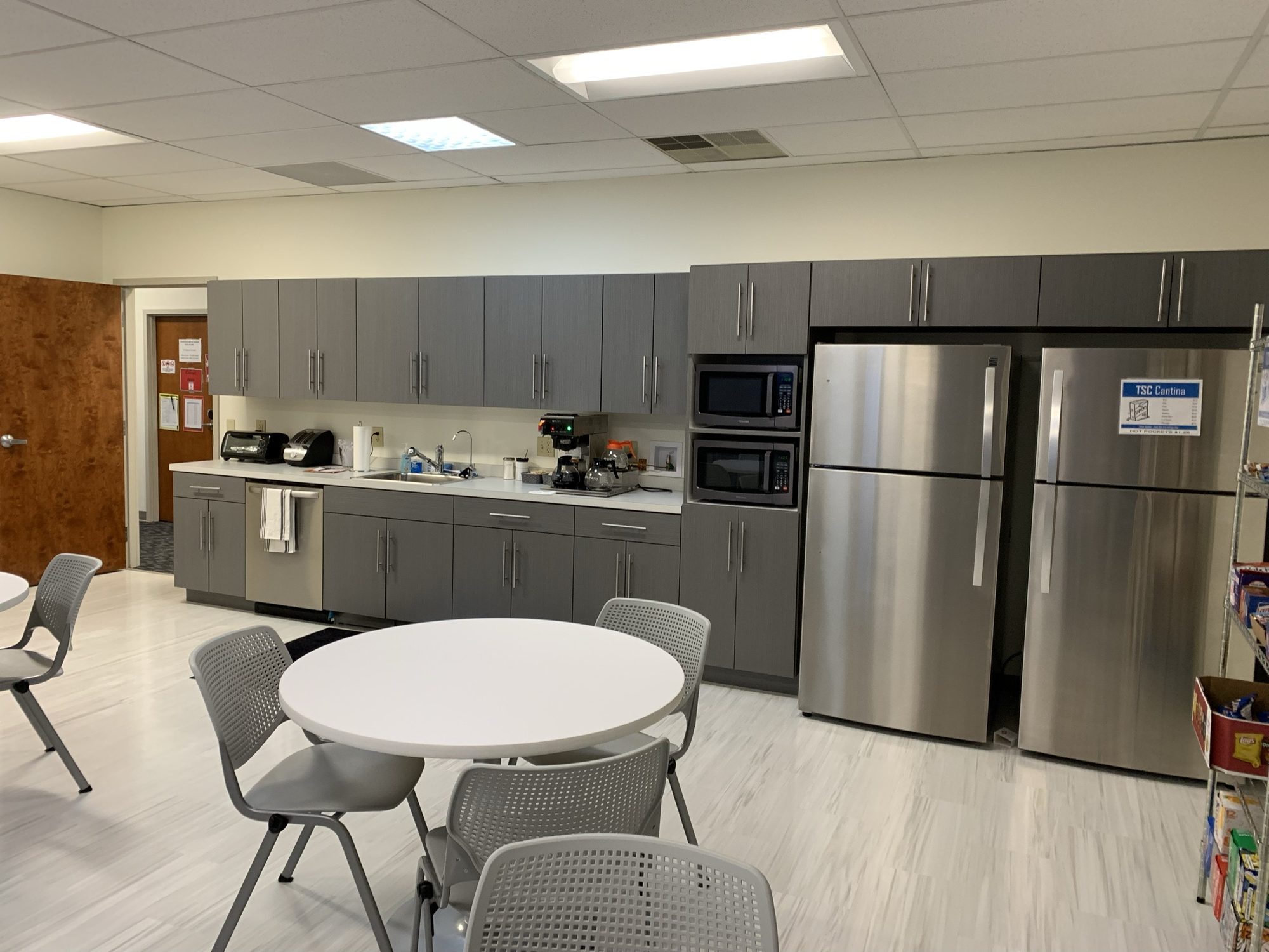 Completed break room with cabinets, appliances, and round tables