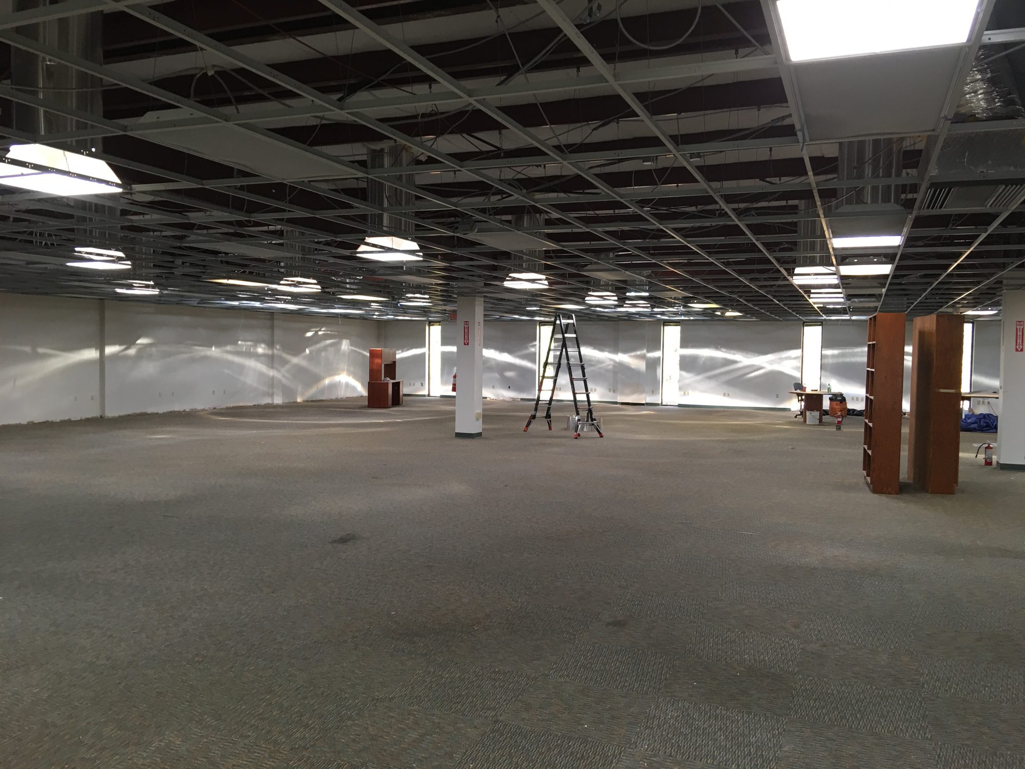 Large open interior prepared for improvement work beneath an exposed ceiling grid
