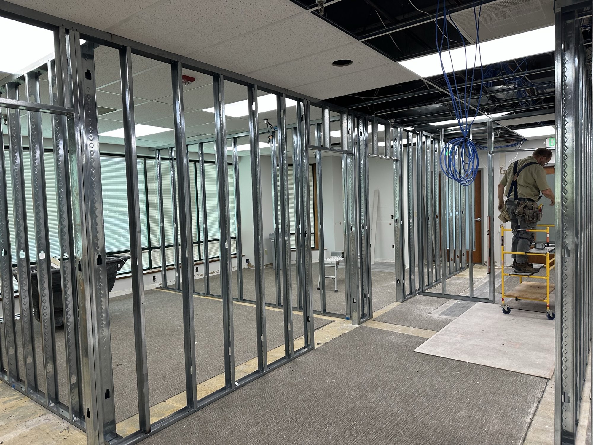 Metal-stud partitions forming new rooms beneath an open ceiling